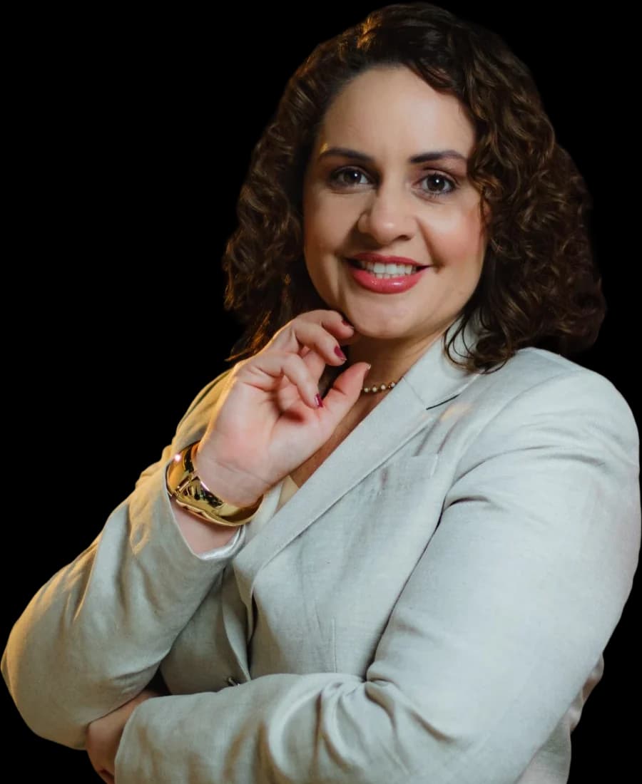 Camila Mota Figueiredo sorrindo, com a mão no queixo, de terno claro